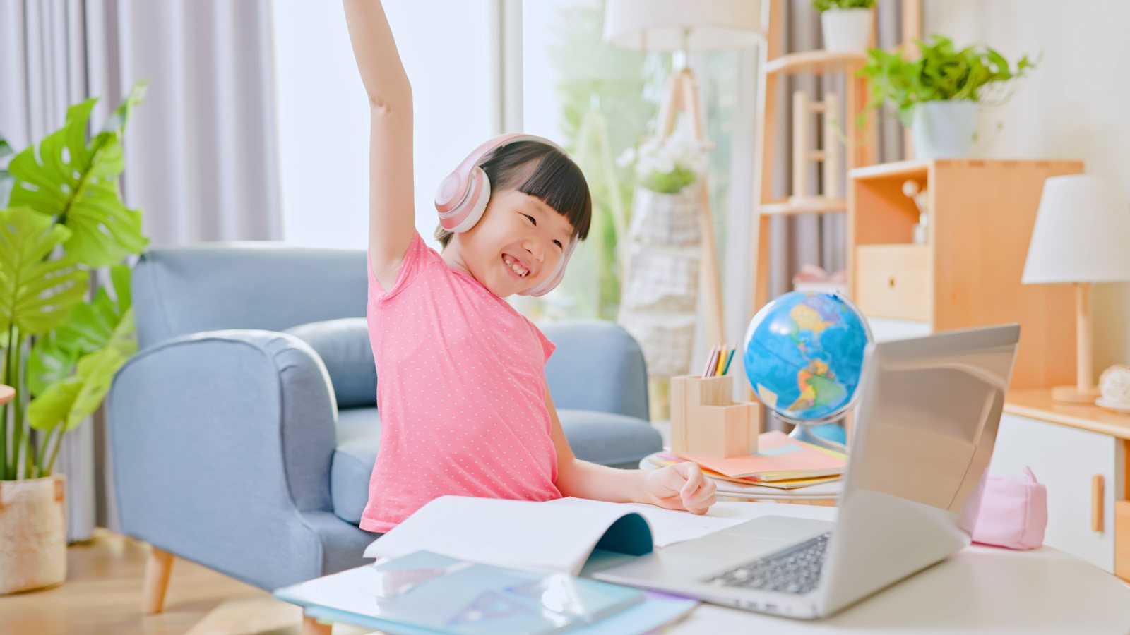 A young student celebrating at her laptop during an online lesson