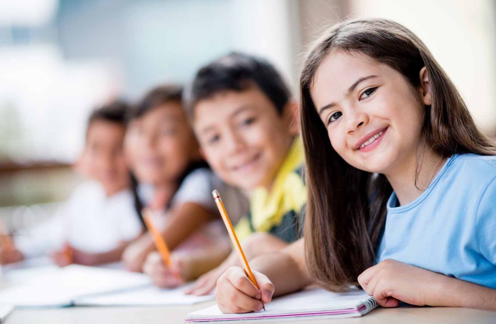 A smiling primary school student writing in her workbook