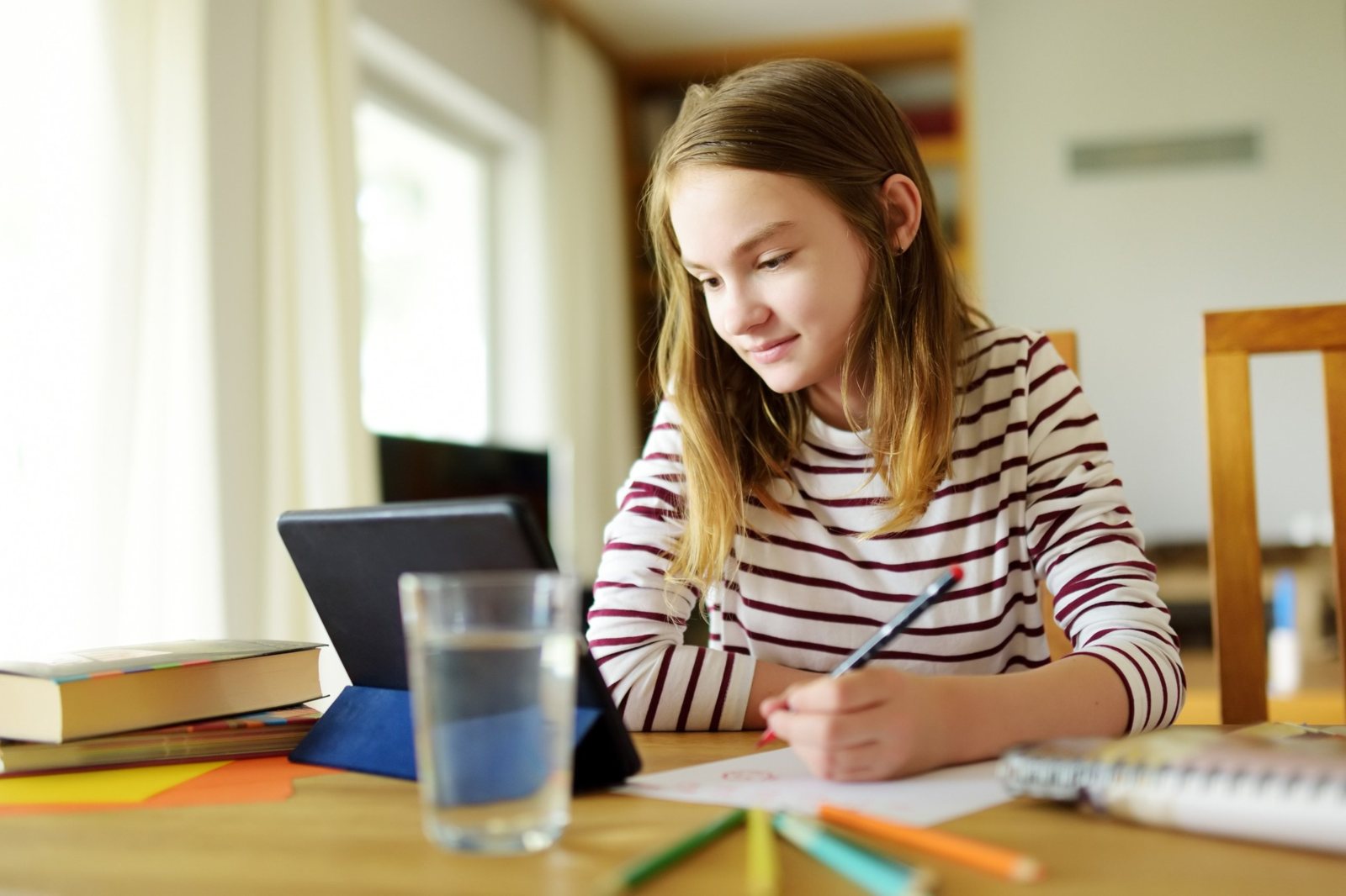A student smiling as she studies at home with a tablet